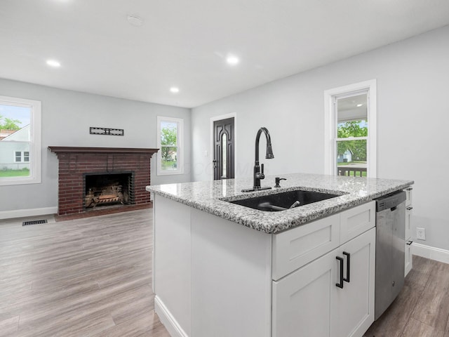 3147 Grasmere Ave, Columbus, OH 43224 - kitchen featuring light stone countertops, light wood-style flooring, stainless steel dishwasher, baseboards, and a sink