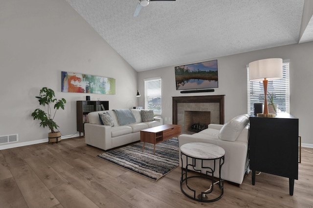 4215 Mack Ct, Powell, OH 43065 - living area featuring a textured ceiling, wood finished floors, a fireplace, a ceiling fan, and plenty of natural light