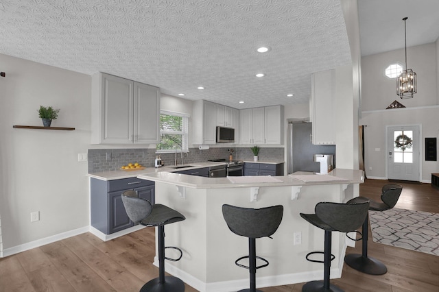 4215 Mack Ct, Powell, OH 43065 - kitchen with stainless steel appliances, a kitchen breakfast bar, a sink, light wood-style flooring, and a textured ceiling
