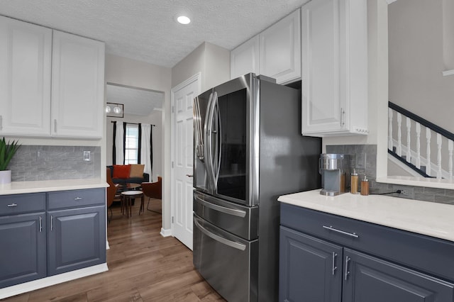 4215 Mack Ct, Powell, OH 43065 - kitchen with stainless steel fridge, white cabinets, decorative backsplash, blue cabinetry, and a textured ceiling