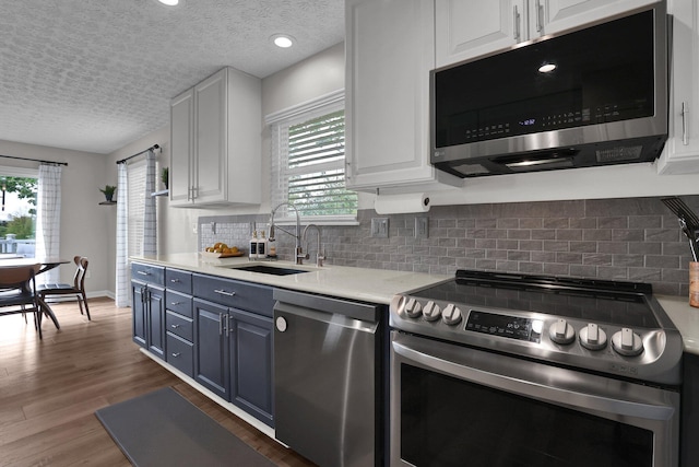 4215 Mack Ct, Powell, OH 43065 - kitchen with appliances with stainless steel finishes, a sink, white cabinetry, healthy amount of natural light, and a textured ceiling