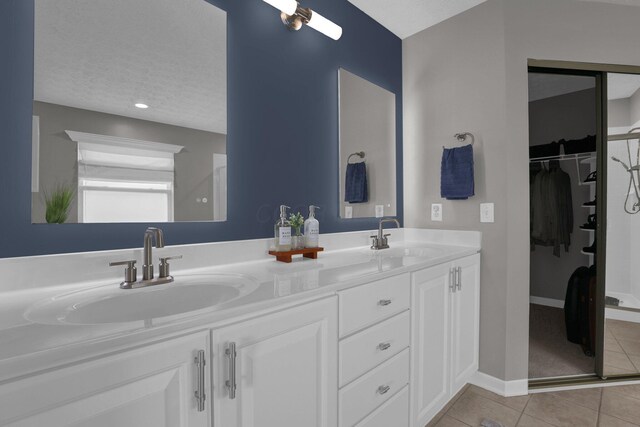 4215 Mack Ct, Powell, OH 43065 - bathroom featuring tile patterned floors, double vanity, a walk in closet, baseboards, and a textured ceiling