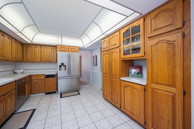 1211 Darcann Dr, Columbus, OH 43220 - kitchen with appliances with stainless steel finishes, brown cabinetry, light countertops, glass insert cabinets, and decorative backsplash