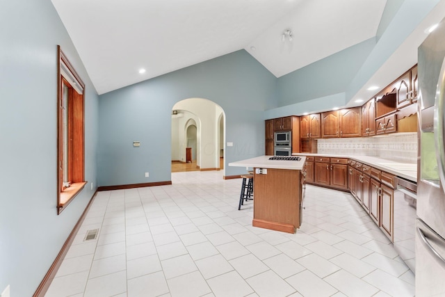 3100 Kropp Rd, Grove City, OH 43123 - kitchen featuring appliances with stainless steel finishes, arched walkways, light countertops, a kitchen bar, and decorative backsplash