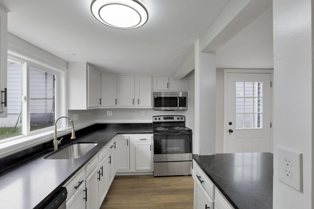 193 Seymour Ave, Buckeye Lake, OH 43008 - kitchen with stainless steel appliances, a sink, light wood-type flooring, dark countertops, and white cabinetry