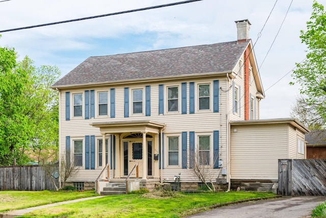 colonial home featuring a chimney and roof with shingles