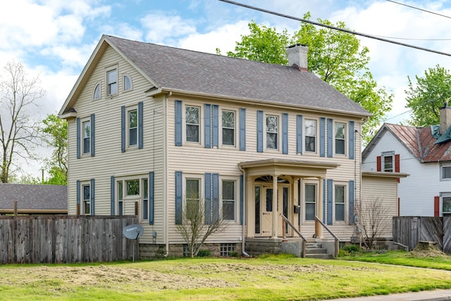 colonial-style house featuring a chimney and roof with shingles