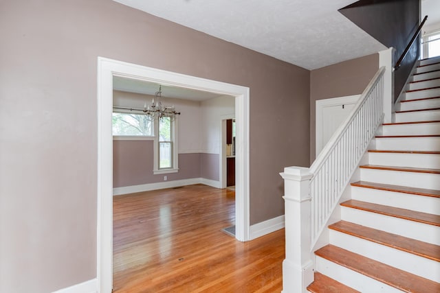 stairway with baseboards, a chandelier, and wood finished floors