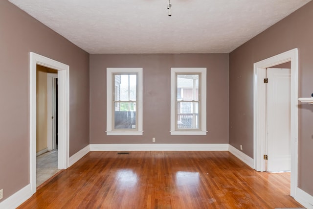 empty room with wood finished floors, baseboards, and a textured ceiling