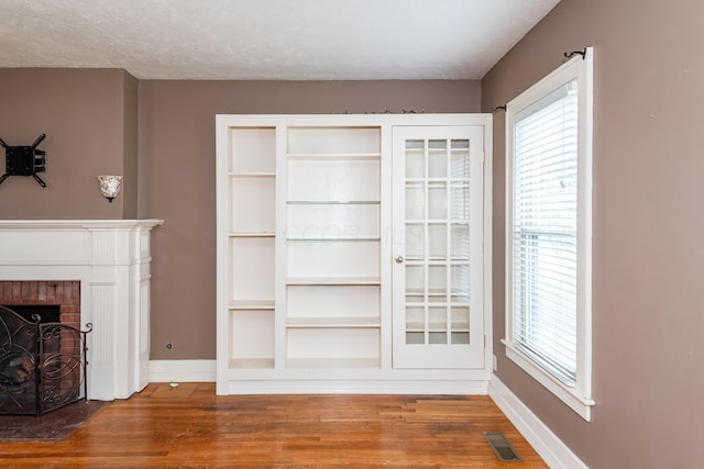 unfurnished living room featuring wood finished floors, baseboards, and plenty of natural light