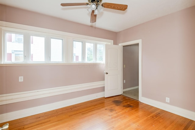 empty room featuring ceiling fan, light wood finished floors, and baseboards