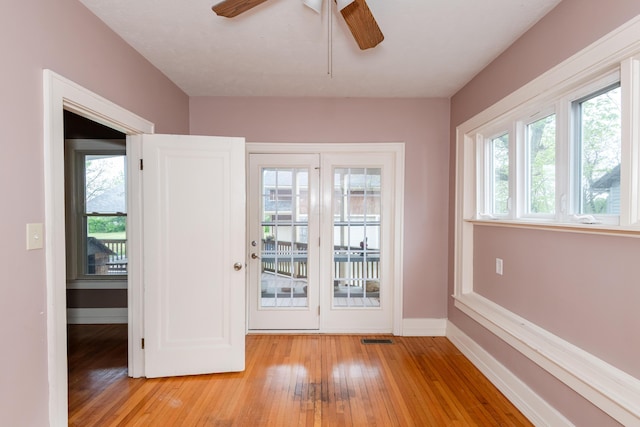doorway to outside featuring healthy amount of natural light, light wood-style floors, ceiling fan, and baseboards