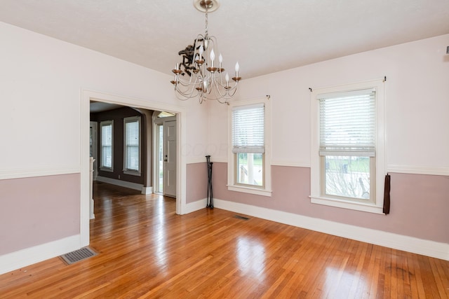 unfurnished dining area featuring baseboards, light wood-style flooring, and a chandelier
