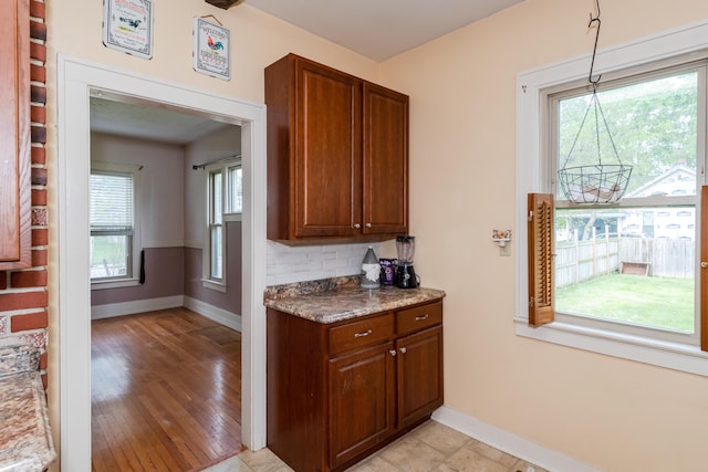 kitchen featuring baseboards, brown cabinets, light wood-style flooring, and hanging light fixtures