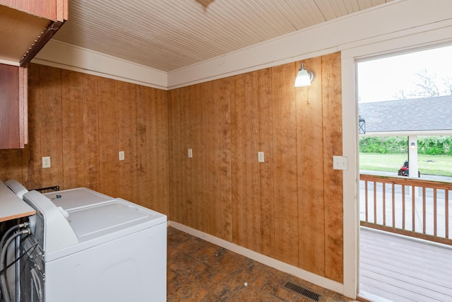 clothes washing area with wood walls, independent washer and dryer, and baseboards