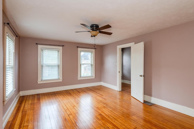 spare room featuring baseboards, light wood-type flooring, and ceiling fan