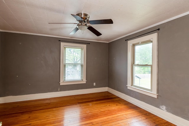 unfurnished room with wood-type flooring, healthy amount of natural light, crown molding, ceiling fan, and baseboards