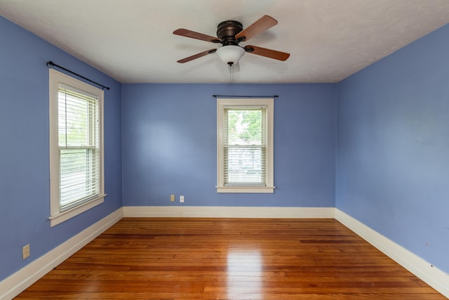 spare room with a ceiling fan, wood-type flooring, and baseboards