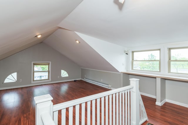 additional living space featuring a baseboard heating unit, dark wood-style floors, vaulted ceiling, and baseboards