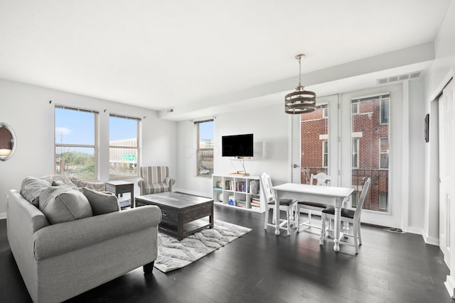 living area with dark wood-style flooring, a chandelier, and baseboards