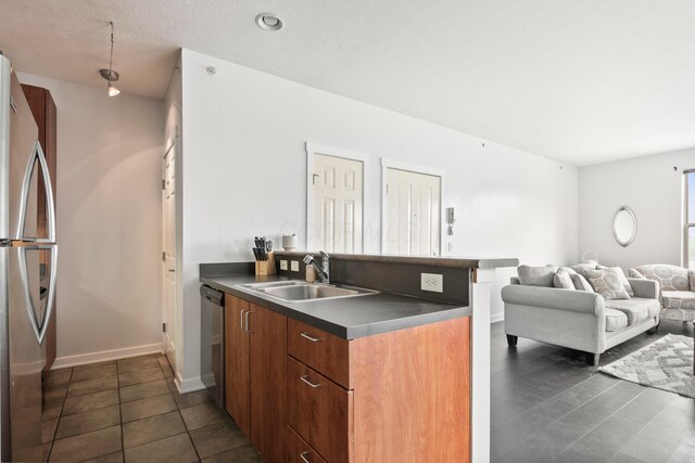 kitchen featuring a sink, stainless steel appliances, open floor plan, dark countertops, and dark tile patterned floors