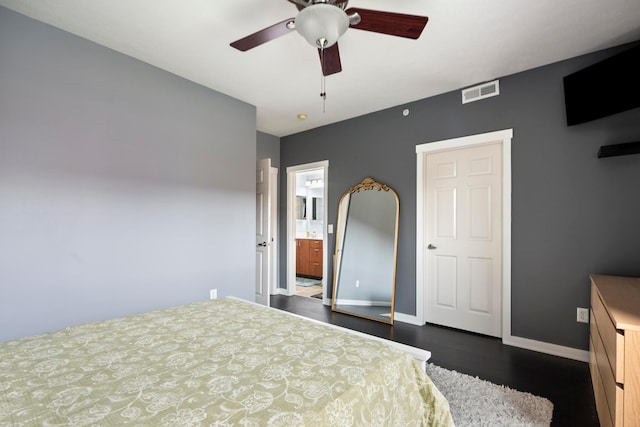 bedroom featuring dark wood finished floors, baseboards, ensuite bathroom, and a ceiling fan