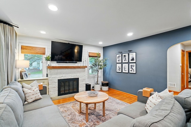 living room with arched walkways, a fireplace, wood finished floors, recessed lighting, and baseboards