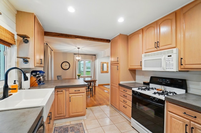 kitchen featuring white microwave, gas stove, a sink, light tile patterned floors, and light brown cabinetry