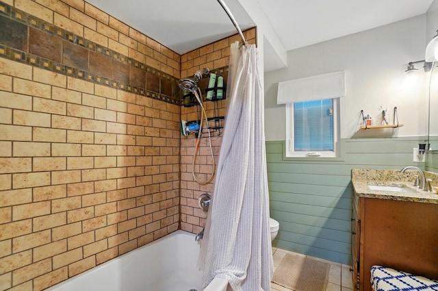 full bath featuring shower / tub combo with curtain, toilet, vanity, a wainscoted wall, and tile patterned flooring