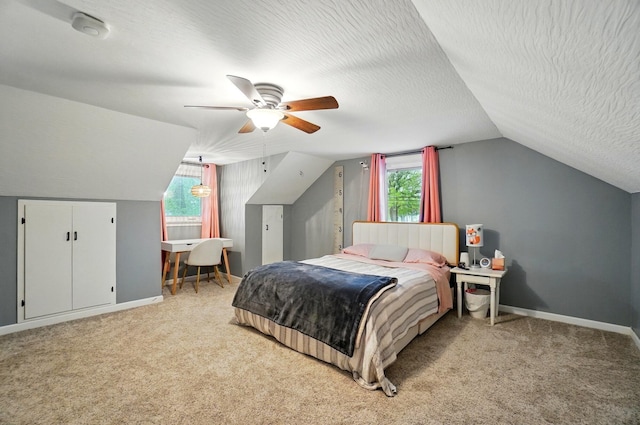 bedroom featuring vaulted ceiling, light carpet, baseboards, ceiling fan, and a textured ceiling