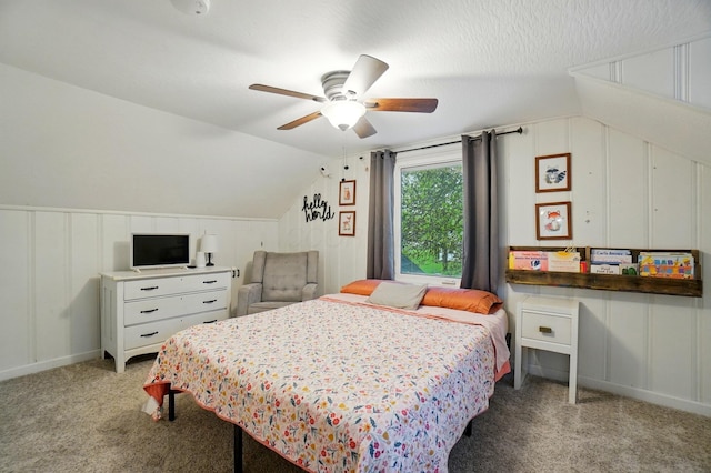 carpeted bedroom featuring a decorative wall, vaulted ceiling, and a ceiling fan