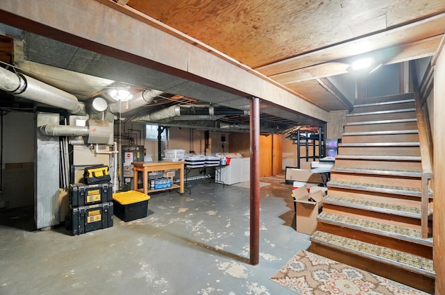 unfinished below grade area with gas water heater, stairway, and separate washer and dryer