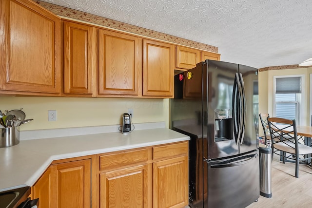 119 Harvard Loop, Delaware, OH 43015 - kitchen featuring black refrigerator with ice dispenser, light countertops, brown cabinetry, light wood-style floors, and electric range