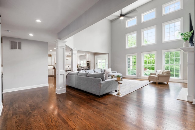9378 Pine Creek Dr, Powell, OH 43065 - living area featuring decorative columns, ceiling fan, healthy amount of natural light, dark wood-style flooring, and a high ceiling