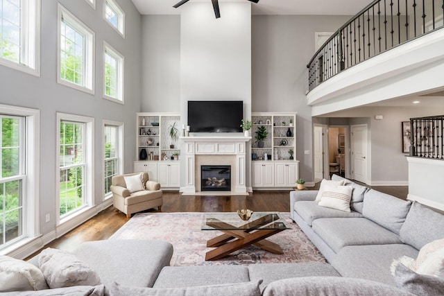 9378 Pine Creek Dr, Powell, OH 43065 - living area with a high ceiling, a fireplace with flush hearth, ceiling fan, dark wood-style flooring, and baseboards