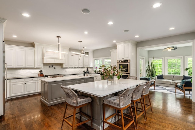 9378 Pine Creek Dr, Powell, OH 43065 - kitchen with a center island, double oven, a breakfast bar, tasteful backsplash, and a sink