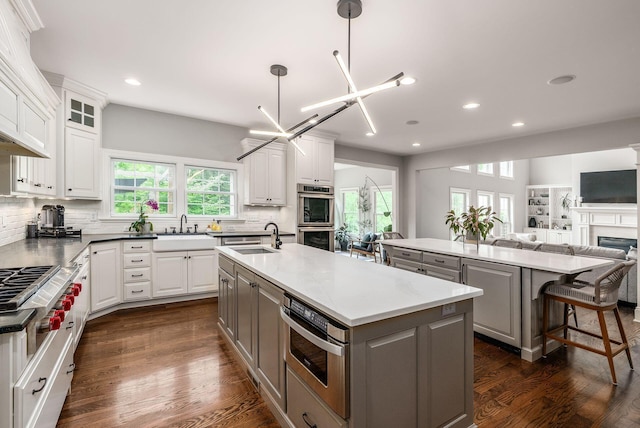 9378 Pine Creek Dr, Powell, OH 43065 - kitchen with a kitchen island with sink, gray cabinetry, a sink, recessed lighting, and appliances with stainless steel finishes