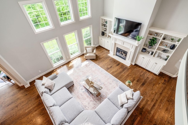 9378 Pine Creek Dr, Powell, OH 43065 - living area featuring a towering ceiling, a fireplace with flush hearth, baseboards, and wood finished floors