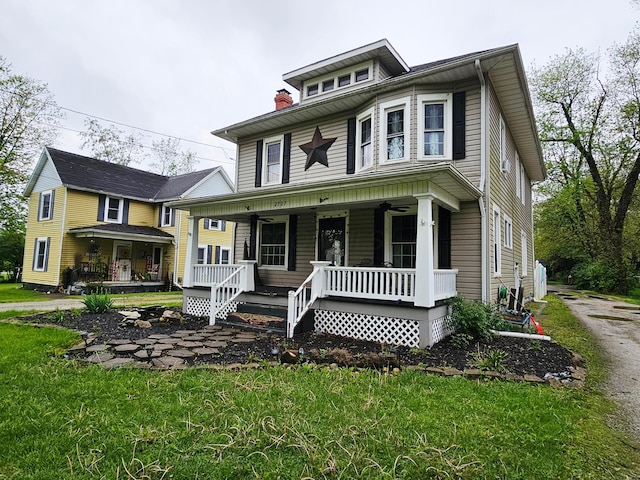 traditional style home with a porch, a front lawn, and a chimney