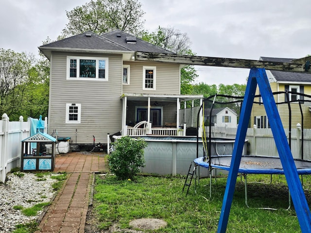back of house with a trampoline, an outdoor pool, and a patio area