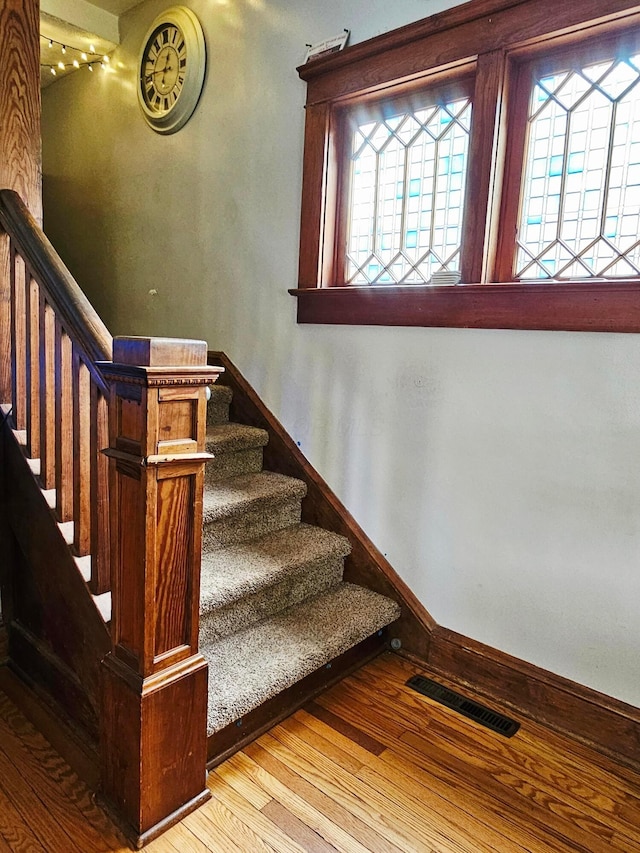 stairs with wood finished floors, baseboards, and track lighting