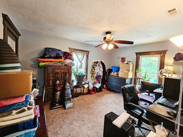 carpeted office featuring ceiling fan and a textured ceiling