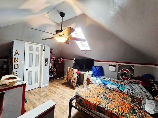 bedroom with vaulted ceiling, a skylight, light wood finished floors, and ceiling fan