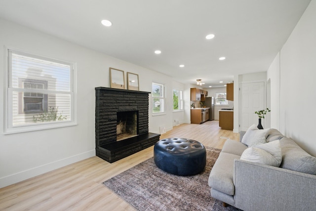 living room with light wood-style flooring, recessed lighting, a fireplace, and baseboards