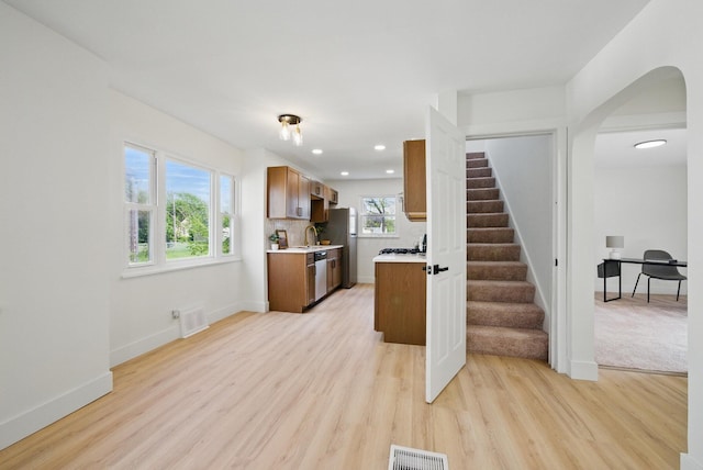 kitchen featuring stainless steel appliances, light countertops, light wood-type flooring, baseboards, and recessed lighting