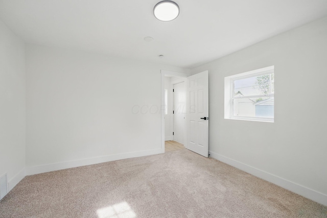unfurnished room featuring light carpet and baseboards