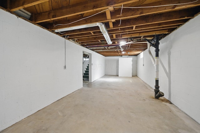 unfinished basement with stairs and concrete block wall