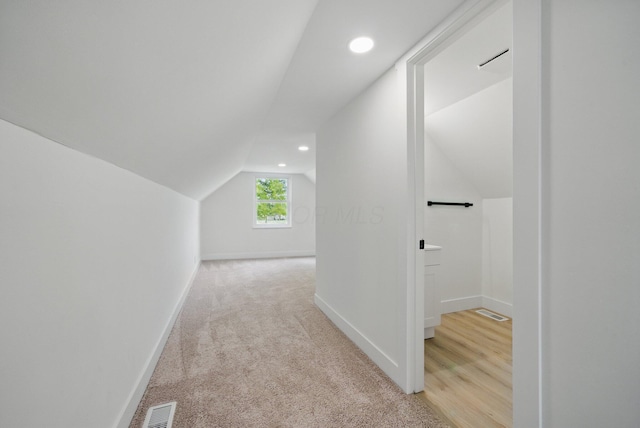 corridor featuring lofted ceiling, baseboards, recessed lighting, and light colored carpet