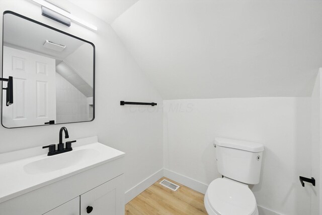 bathroom with wood finished floors, baseboards, toilet, vanity, and vaulted ceiling