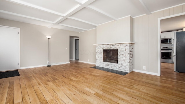 255 S Preston St, Centerburg, OH 43011 - unfurnished living room with beam ceiling, light wood finished floors, a brick fireplace, and baseboards